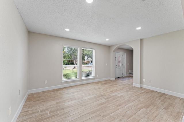 4519 Pioneer Trl, Sugar Land, TX 77479 - unfurnished room featuring light wood-style flooring, arched walkways, a textured ceiling, recessed lighting, and baseboards