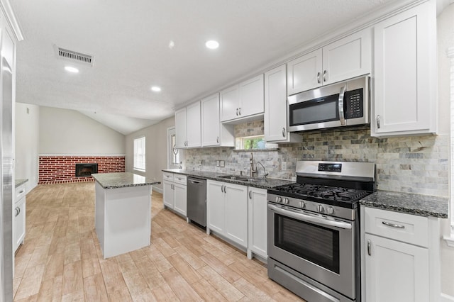 4519 Pioneer Trl, Sugar Land, TX 77479 - kitchen with appliances with stainless steel finishes, a sink, light wood finished floors, white cabinets, and lofted ceiling