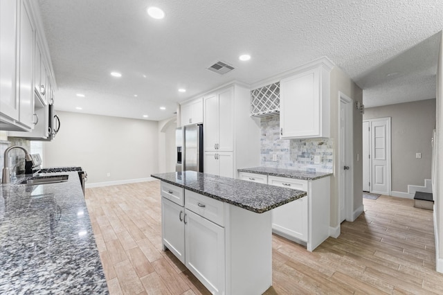 4519 Pioneer Trl, Sugar Land, TX 77479 - kitchen with stainless steel refrigerator with ice dispenser, a sink, arched walkways, light wood-style flooring, and a textured ceiling