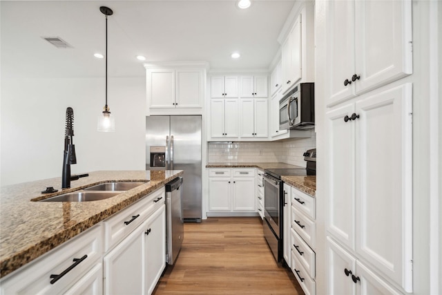 5402 Jonathan Ln, Houston, TX 77011 - kitchen with stainless steel appliances, a sink, white cabinets, decorative light fixtures, and recessed lighting