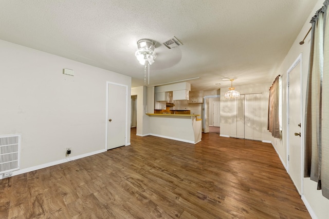 7306 Nightingale Cir, Texas City, TX 77591 - unfurnished living room with dark wood-type flooring, ceiling fan, a chandelier, baseboards, and a textured ceiling