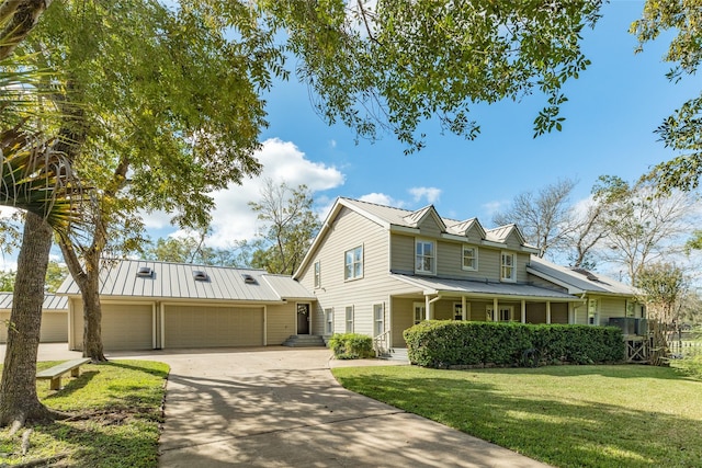 14001/14009 W Hughes Rd, Dickinson, TX 77539 - view of front of property featuring a front lawn, driveway, a garage, metal roof, and a standing seam roof