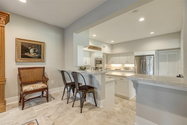 14001/14009 W Hughes Rd, Dickinson, TX 77539 - kitchen with appliances with stainless steel finishes, a breakfast bar, white cabinetry, a peninsula, and light countertops