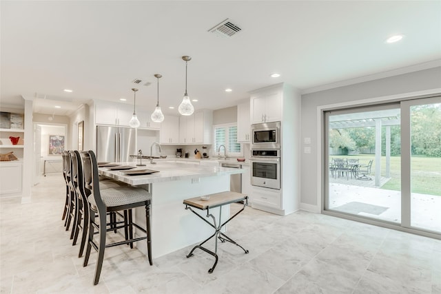 14001/14009 W Hughes Rd, Dickinson, TX 77539 - kitchen featuring stainless steel appliances, crown molding, healthy amount of natural light, a kitchen breakfast bar, and white cabinetry