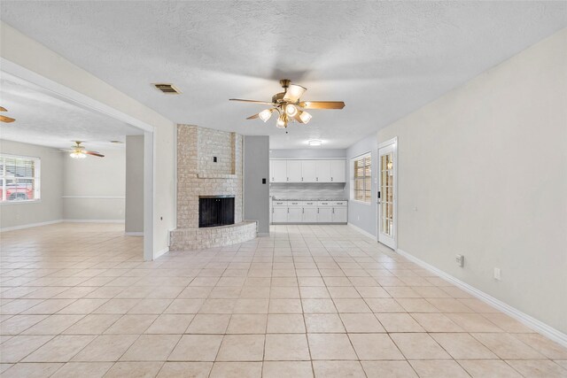 1102 Brenda Dr, Deer Park, TX 77536 - unfurnished living room featuring ceiling fan, a fireplace, light tile patterned floors, a textured ceiling, and baseboards