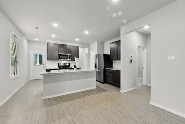 25707 Hickory Pecan Trl, Tomball, TX 77375 - kitchen with appliances with stainless steel finishes, light wood-style flooring, baseboards, a center island with sink, and recessed lighting