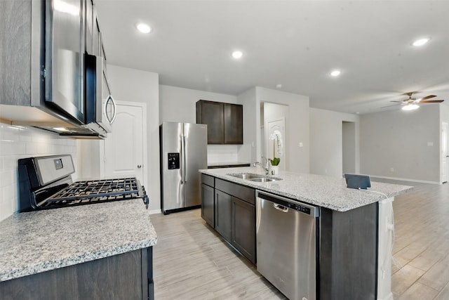 25707 Hickory Pecan Trl, Tomball, TX 77375 - kitchen with appliances with stainless steel finishes, a sink, tasteful backsplash, light wood finished floors, and a ceiling fan