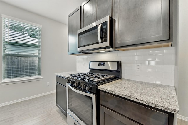 25707 Hickory Pecan Trl, Tomball, TX 77375 - kitchen featuring appliances with stainless steel finishes, baseboards, tasteful backsplash, light wood finished floors, and dark brown cabinets