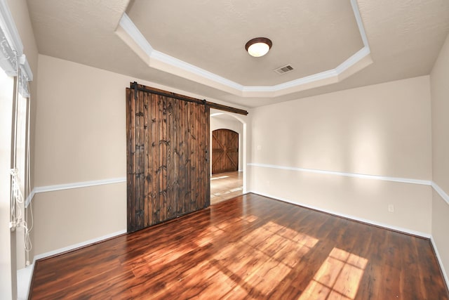 14311 Lakepointe Bend Ln, Cypress, TX 77429 - empty room with a tray ceiling, a barn door, wood finished floors, arched walkways, and crown molding