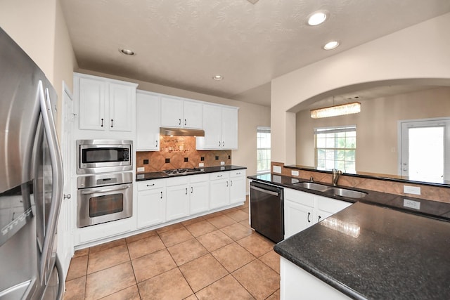 14311 Lakepointe Bend Ln, Cypress, TX 77429 - kitchen featuring appliances with stainless steel finishes, a sink, under cabinet range hood, light tile patterned floors, and tasteful backsplash