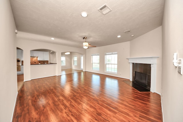14311 Lakepointe Bend Ln, Cypress, TX 77429 - unfurnished living room featuring a ceiling fan, dark wood-style floors, recessed lighting, a tile fireplace, and arched walkways