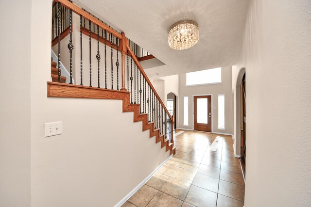 14311 Lakepointe Bend Ln, Cypress, TX 77429 - foyer entrance with arched walkways, a chandelier, tile patterned floors, stairway, and baseboards