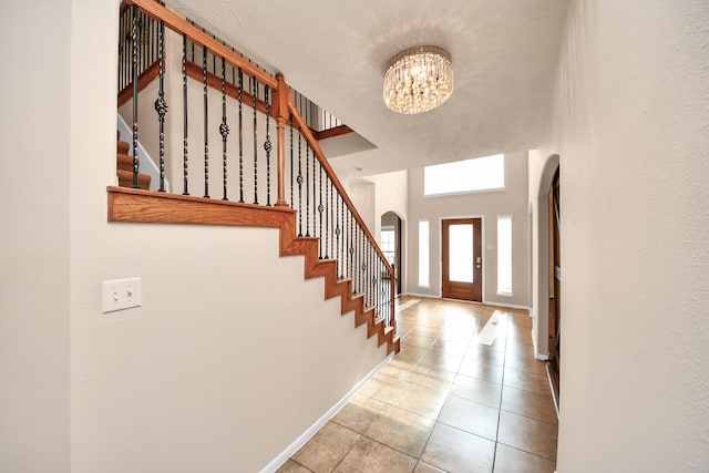 14311 Lakepointe Bend Ln, Cypress, TX 77429 - tiled entryway featuring arched walkways, a chandelier, stairway, baseboards, and a high ceiling