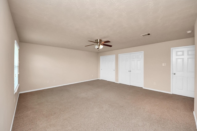 14311 Lakepointe Bend Ln, Cypress, TX 77429 - unfurnished bedroom featuring multiple closets, carpet floors, baseboards, a ceiling fan, and a textured ceiling