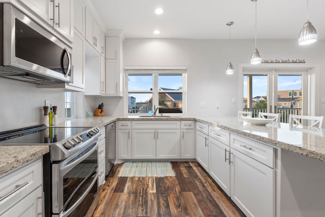 22516 Bay Point Dr, Galveston, TX 77554 - kitchen featuring stainless steel appliances, a sink, dark wood-style floors, white cabinetry, and healthy amount of natural light