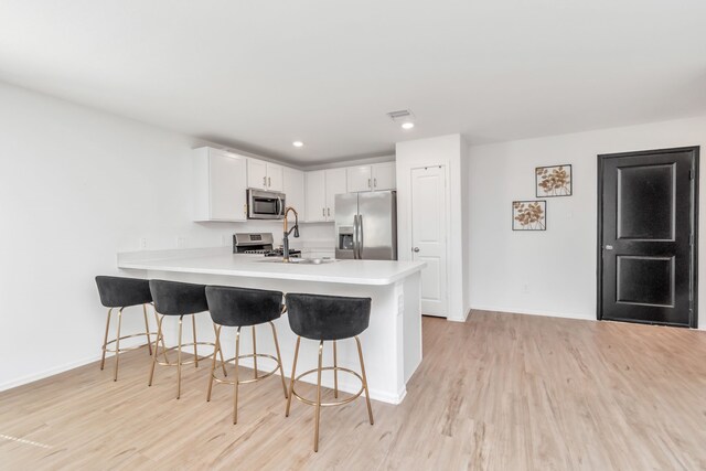 18110 Mendocino Ridge Ln, Hockley, TX 77447 - kitchen featuring appliances with stainless steel finishes, a peninsula, a breakfast bar area, light wood finished floors, and recessed lighting