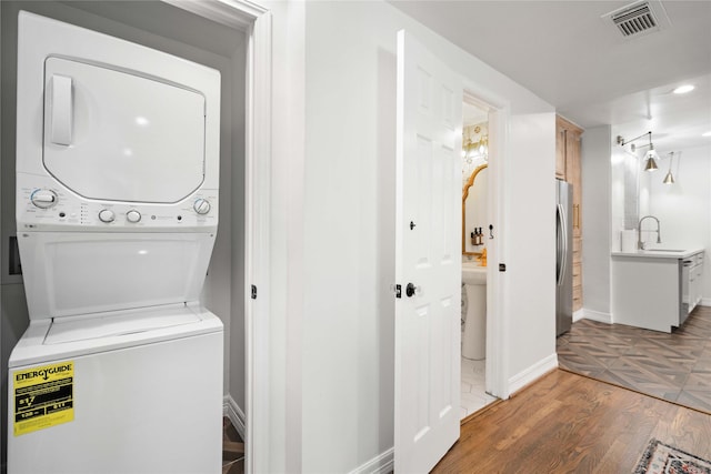 5004 Park Dr, Houston, TX 77023 - washroom featuring stacked washer / dryer, light wood-style floors, and recessed lighting