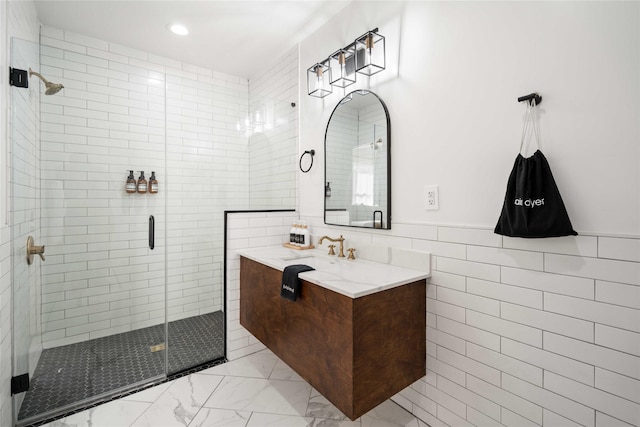 5004 Park Dr, Houston, TX 77023 - bathroom with a shower stall, vanity, marble look tile flooring, tile walls, and recessed lighting