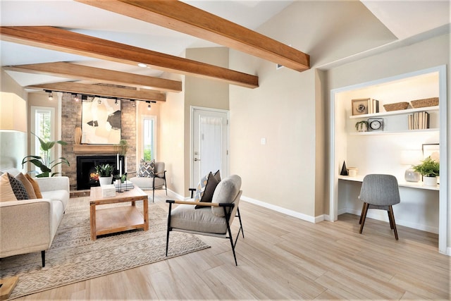 5927 Maco St, Galveston, TX 77551 - living room with beam ceiling, a brick fireplace, light wood-type flooring, baseboards, and healthy amount of natural light