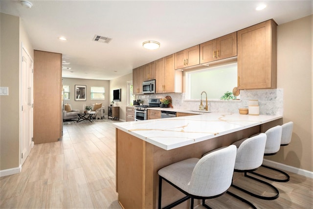 5927 Maco St, Galveston, TX 77551 - kitchen featuring stainless steel appliances, a sink, light stone counters, tasteful backsplash, and a kitchen breakfast bar