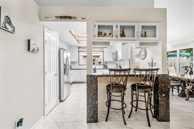 5330 Pine Cliff Dr, Houston, TX 77084 - kitchen featuring appliances with stainless steel finishes, a kitchen breakfast bar, light marble finish flooring, glass insert cabinets, and plenty of natural light