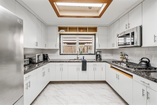 5330 Pine Cliff Dr, Houston, TX 77084 - kitchen with stainless steel appliances, a sink, a tray ceiling, light marble finish flooring, and white cabinetry