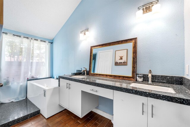 5330 Pine Cliff Dr, Houston, TX 77084 - full bath featuring double vanity, vaulted ceiling, wood finish floors, and a tub