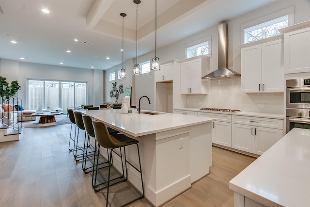 1514 Laird St Unit A, Houston, TX 77008 - kitchen with wall chimney range hood, a sink, stainless steel double oven, light wood finished floors, and decorative backsplash