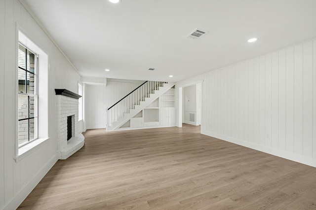 124 Rolling Wood Dr, Baytown, TX 77520 - unfurnished living room with light wood-type flooring, a fireplace, a decorative wall, stairway, and recessed lighting
