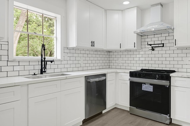 124 Rolling Wood Dr, Baytown, TX 77520 - kitchen featuring gas stove, wall chimney exhaust hood, stainless steel dishwasher, a sink, and light wood-style flooring