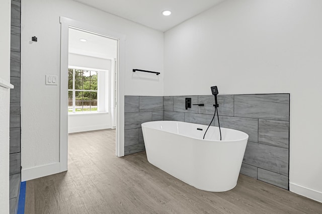 124 Rolling Wood Dr, Baytown, TX 77520 - bathroom with wood finished floors, a soaking tub, tile walls, baseboards, and recessed lighting