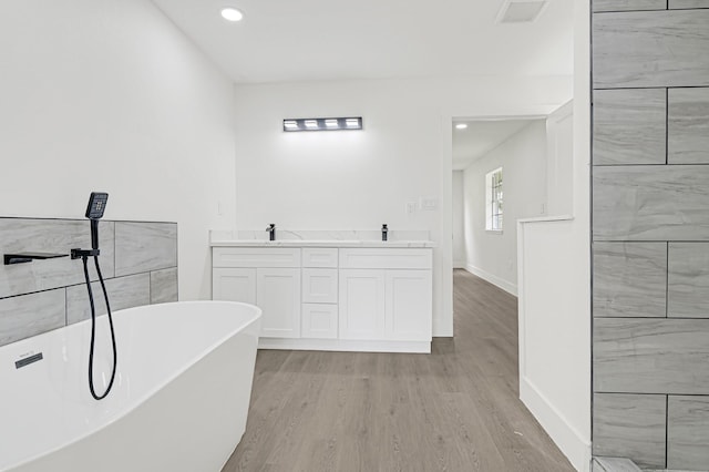 124 Rolling Wood Dr, Baytown, TX 77520 - full bathroom featuring a soaking tub, wood finished floors, baseboards, recessed lighting, and double vanity