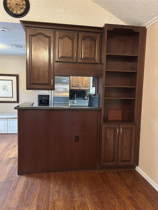 13802 Waterville Way, Houston, TX 77015 - kitchen with a textured ceiling, dark wood-style flooring, dark countertops, dark brown cabinetry, and stainless steel refrigerator