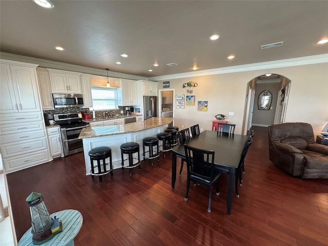 2108 Mills, Crystal Beach, TX 77650 - dining area with arched walkways, ornamental molding, dark wood-type flooring, and recessed lighting