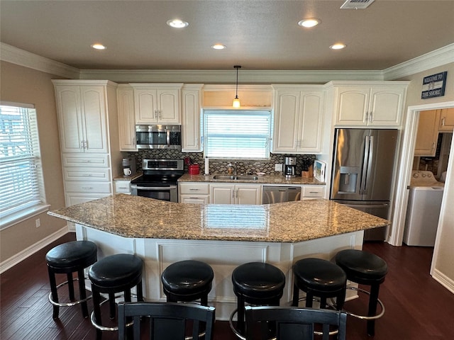 2108 Mills, Crystal Beach, TX 77650 - kitchen featuring stainless steel appliances, washer / dryer, a sink, ornamental molding, and a kitchen breakfast bar