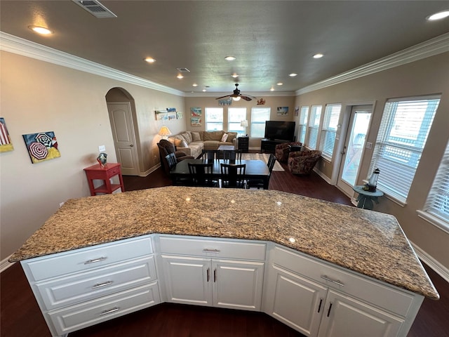 2108 Mills, Crystal Beach, TX 77650 - kitchen with dark wood-style floors, arched walkways, baseboards, ceiling fan, and white cabinetry