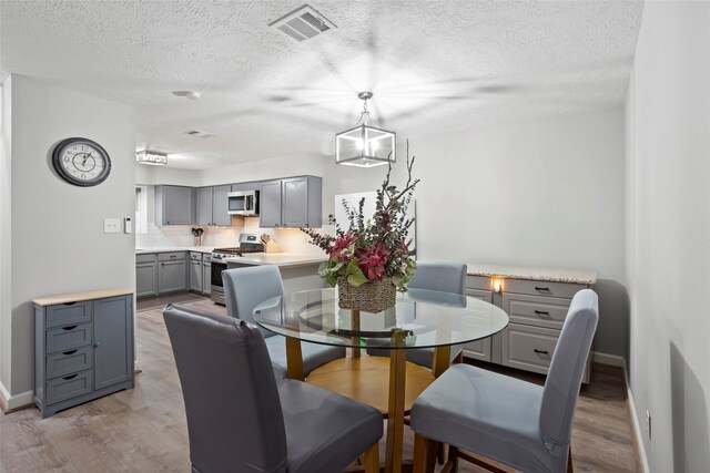654 W Country Grove Cir, Pearland, TX 77584 - dining space featuring light wood-type flooring, a textured ceiling, and baseboards