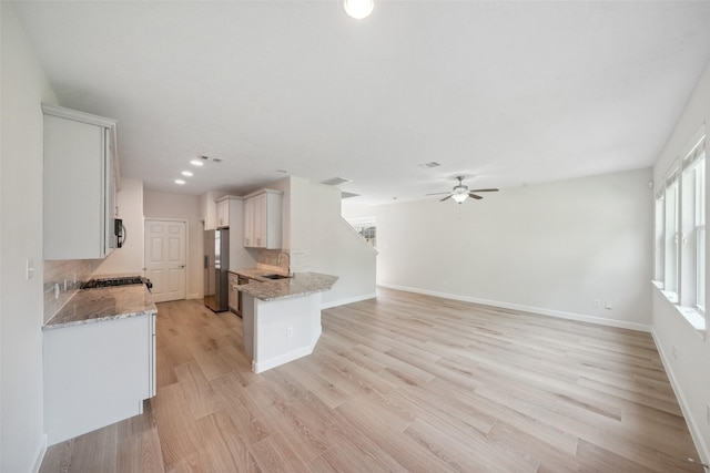 10 Fairlee Ct, The Woodlands, TX 77354 - kitchen featuring appliances with stainless steel finishes, a sink, a ceiling fan, light stone countertops, and light wood-style flooring