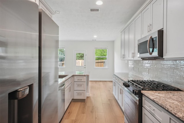 10 Fairlee Ct, The Woodlands, TX 77354 - kitchen featuring appliances with stainless steel finishes, light wood-style flooring, decorative backsplash, recessed lighting, and baseboards