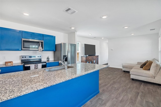 11947 Midas Ln, Willis, TX 77378 - kitchen with appliances with stainless steel finishes, blue cabinetry, a sink, light stone counters, and dark wood finished floors