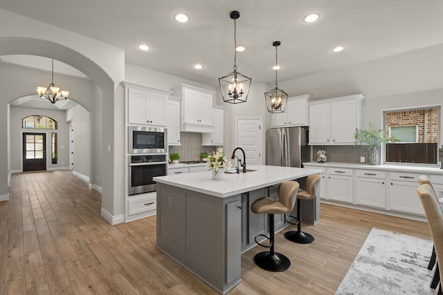 2915 Finch Ct, Katy, TX 77493 - kitchen with appliances with stainless steel finishes, a sink, arched walkways, decorative backsplash, and recessed lighting