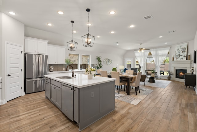 2915 Finch Ct, Katy, TX 77493 - kitchen featuring appliances with stainless steel finishes, a sink, gray cabinets, a ceiling fan, and a glass covered fireplace