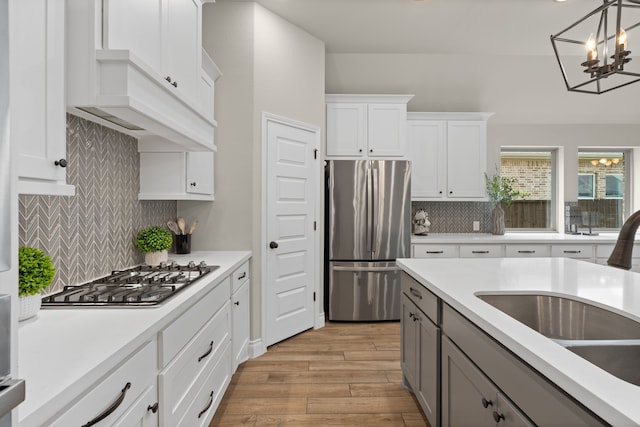 2915 Finch Ct, Katy, TX 77493 - kitchen featuring stainless steel appliances, a sink, light wood-style flooring, backsplash, and light countertops
