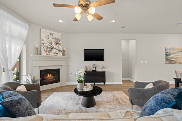 2915 Finch Ct, Katy, TX 77493 - living room featuring a ceiling fan, a glass covered fireplace, recessed lighting, light wood-style floors, and baseboards