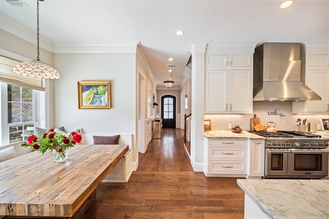 2202 Sul Ross St, Houston, TX 77098 - kitchen with wall chimney range hood, double oven range, plenty of natural light, white cabinetry, and crown molding