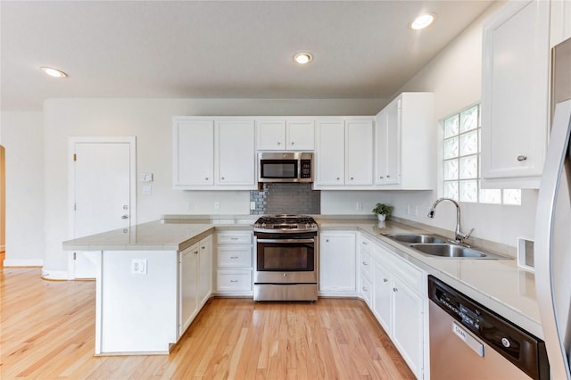 3721 Main Poplar Dr, Houston, TX 77025 - kitchen with stainless steel appliances, a sink, a peninsula, light wood-style flooring, and white cabinets