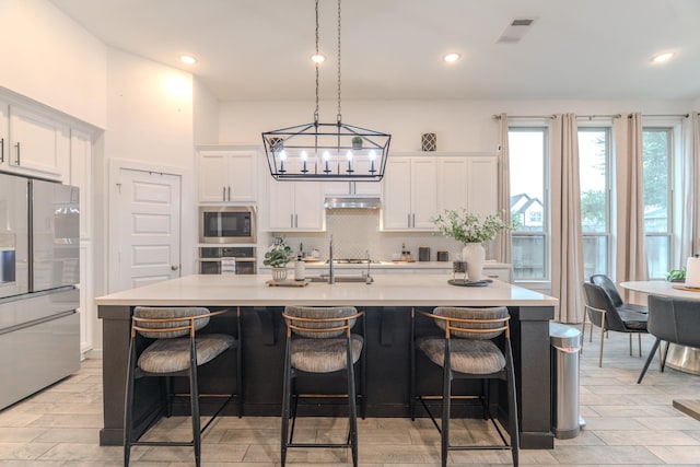 30707 Thicket Ct, Fulshear, TX 77441 - kitchen featuring stainless steel appliances, white cabinets, a center island with sink, under cabinet range hood, and recessed lighting