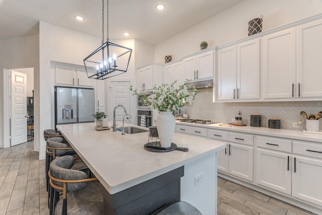 30707 Thicket Ct, Fulshear, TX 77441 - kitchen featuring stainless steel appliances, decorative backsplash, white cabinets, pendant lighting, and an island with sink