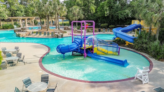 18002 Outback Lakes Trl, Humble, TX 77346 - community pool featuring a water slide, a water play area, view of wooded area, a patio, and a pergola