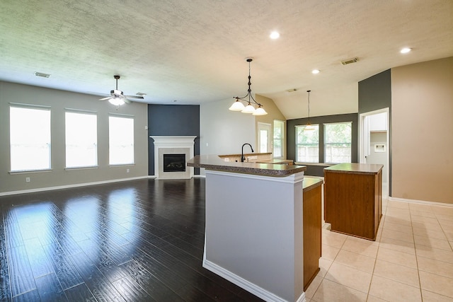 18002 Outback Lakes Trl, Humble, TX 77346 - kitchen with a kitchen island with sink, a glass covered fireplace, plenty of natural light, baseboards, and recessed lighting